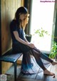 A woman sitting on a bench in front of a window.